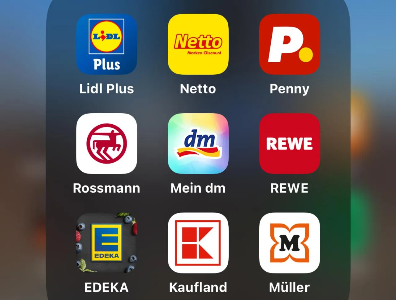 Neun App-Logos in einem Ordner auf dem Smartphone: Lidl, Penny, Netto, Rewe, Rossmann, dm, Edeka, Kaufland und Müller.