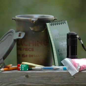 Geöffnete Geocache Dose. Die Inhalte stehen daneben.