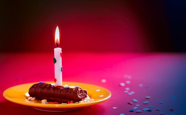 Foto einer brennenden kleinen Kerze, die auf einer Süßigkeit steht. Farben in rot gehalten