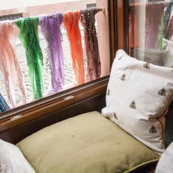 Mit Kissen ausgestaltete Sitzecke auf der Fensterbanck, draußen sind bunte Halstücher angebunden