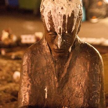 Skulptur eines Zeitungslesenden Mannes, der am Kopf mit Wachs beschmutzt ist