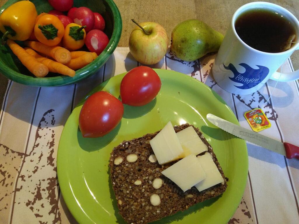Blick auf das Frühstück mit verschiedenem Gemüse, Käse, Vollkornbrot und eine Literaturcamp-Tasse mit Tee