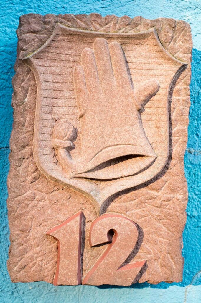 Stein mit Handschuh-Wappen und der Hausnummer 12.