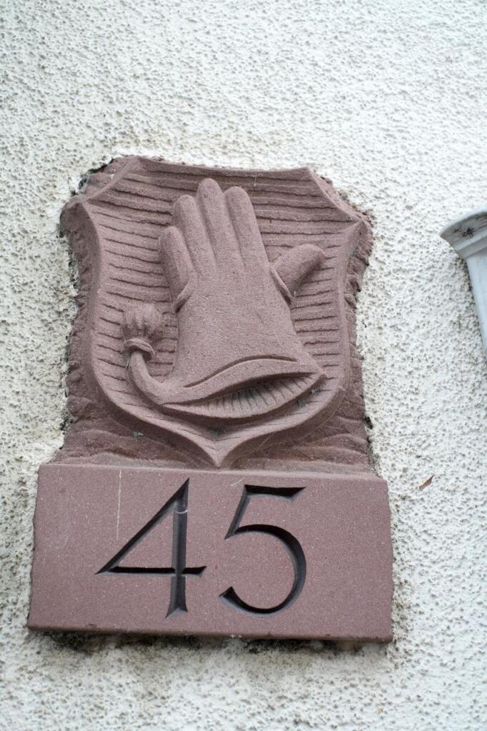Steinplatte gemeißelt. Hausnummer 45 und Handschuh-Wappen.
