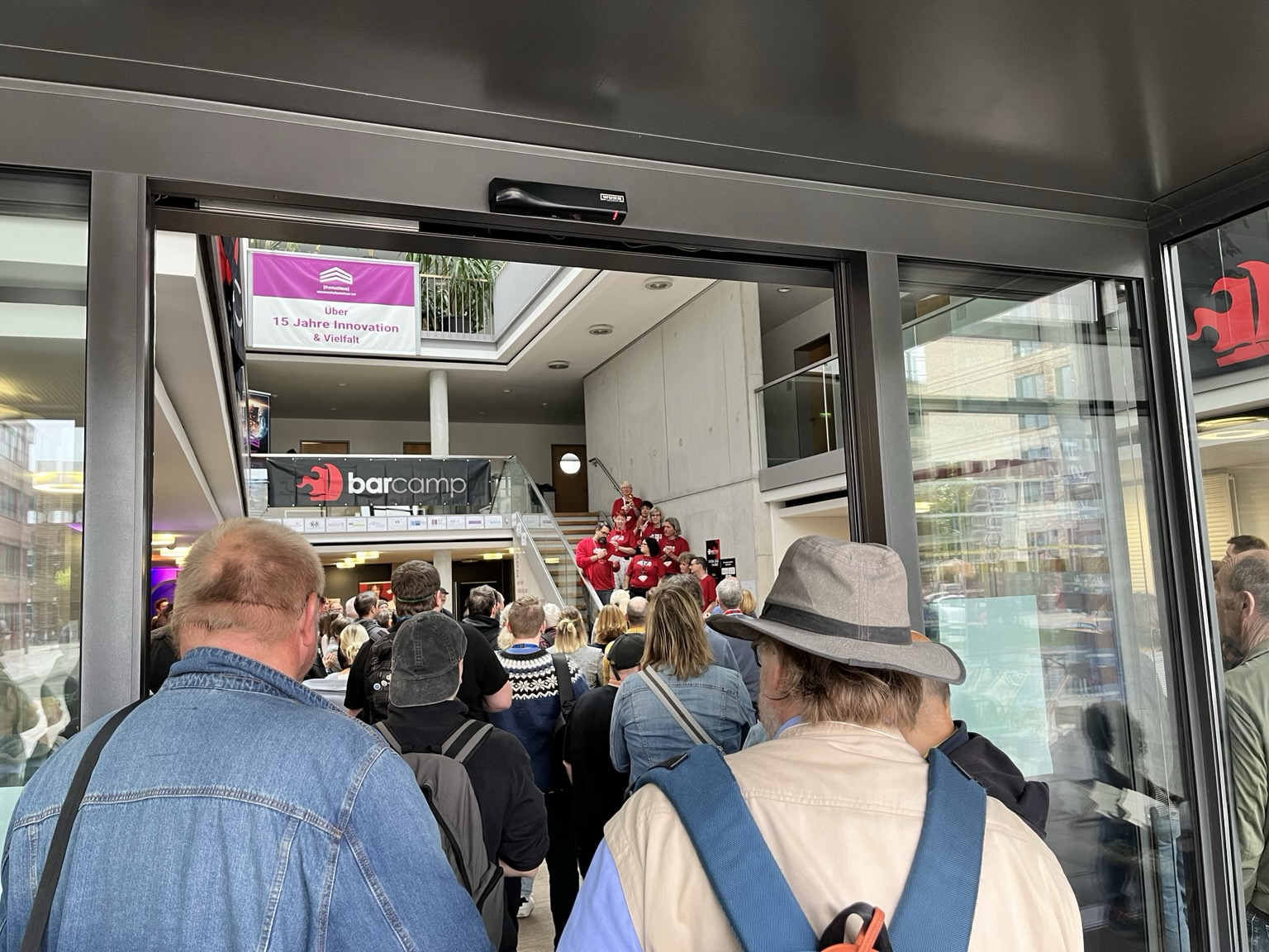 Das Orgateam steht erhöht auf einer Treppe und begrüßt das Publikum. 