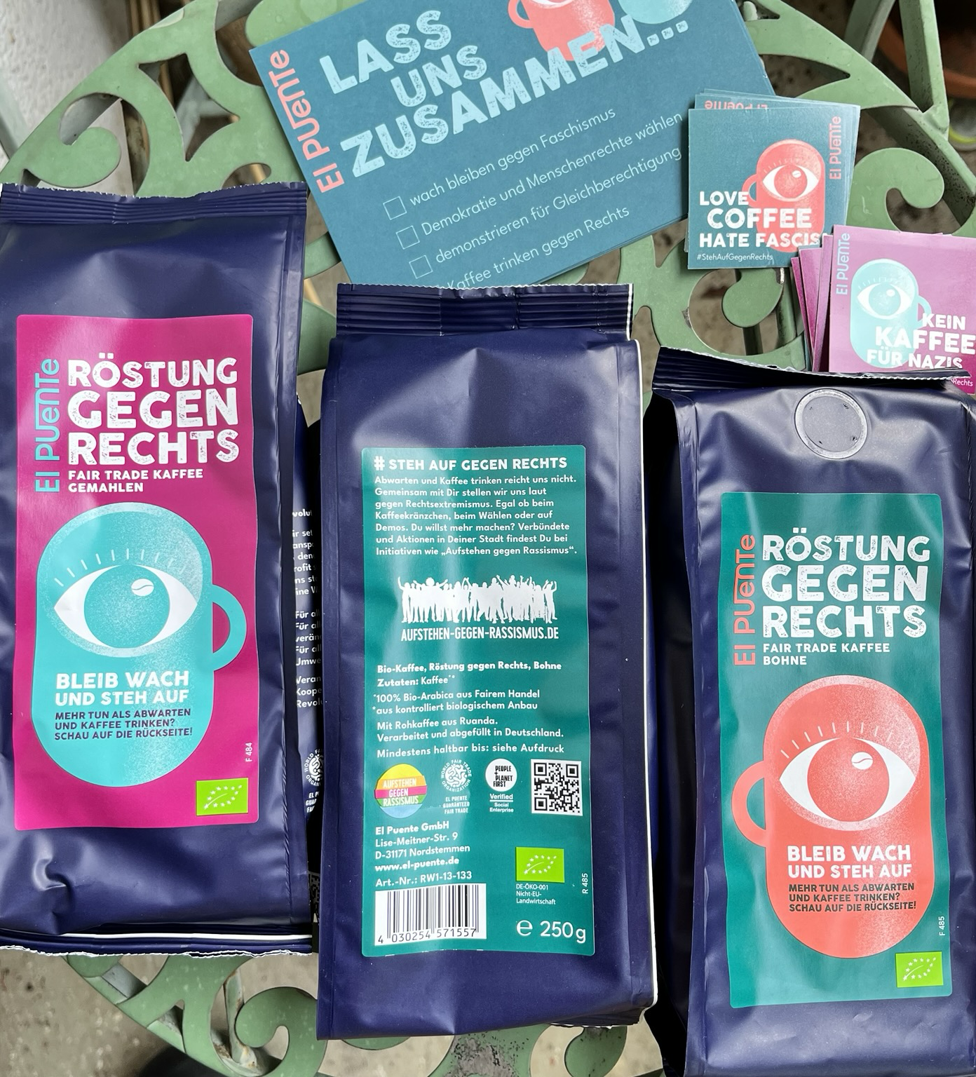 Drei Packungen Röstung gegen rechts mit je 250 Gramm, Sticker und Postkarten. 