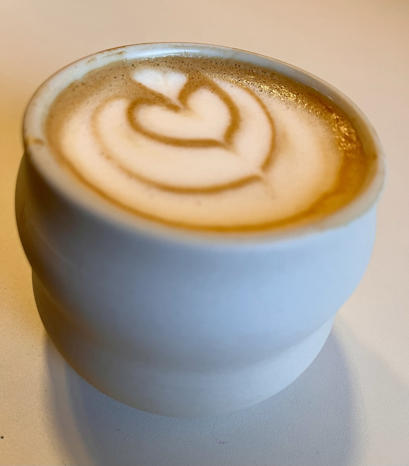 Eine Tasse Kaffee mit Latteart. Ein Herz ist zu erkennen. 